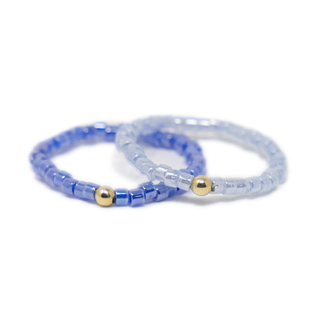 Two purple beaded rings with gold beads on a white background
