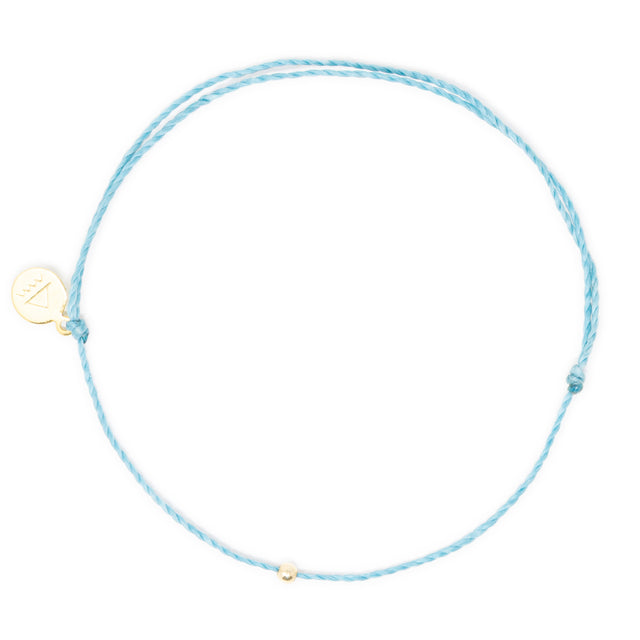 Teal thread ankle bracelet with gold bead on white top view