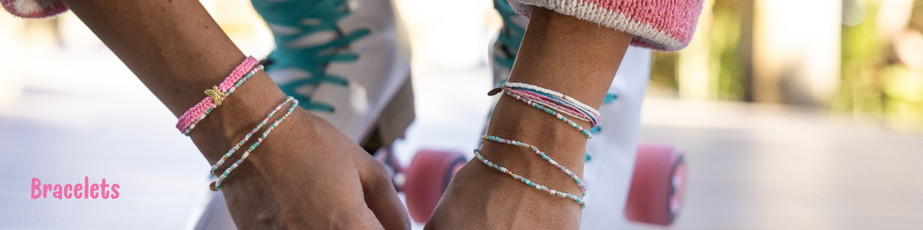 Model on skates with pink & teal bracelets stacked on both wrists 