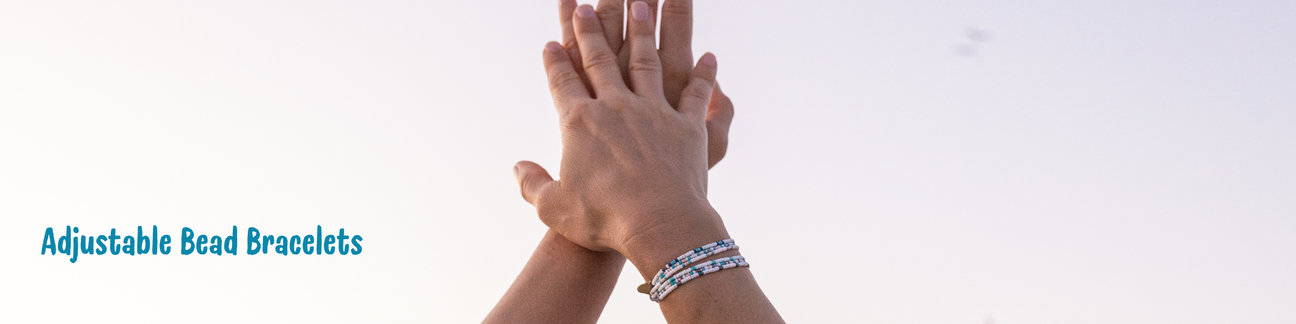 Hands up in the sky with multiple beaded bracelets on one wrist