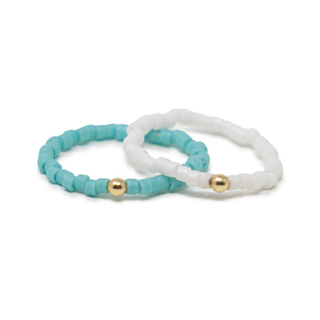 Two beaded rings, one turquoise and one white, with gold beads on a white background.