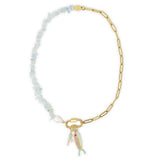 Necklace with gold chain and aquamarine beads and multicolored fish and stone charms on a white background