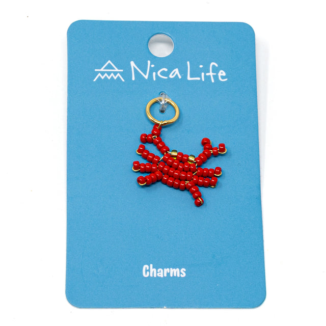Hand beaded crab charm shown on blue Nica Life branded card