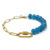 Bracelet with blue stone beads and gold chain with a gold carabiner for charms on a white background