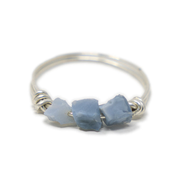 three raw blue opal stones on a silver ring shown on white