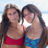 Women wearing seed bead chokers standing on a beach