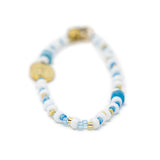 Beaded bag charm with blue and gold accents on a white background