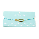 Blues & gold beaded charm bar anklet with carabiner clasp for charms show on teal Nica Life branded card.
