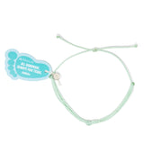 Light mint color string knot anklet with a Nica LIfe branded foot shaped tag on white