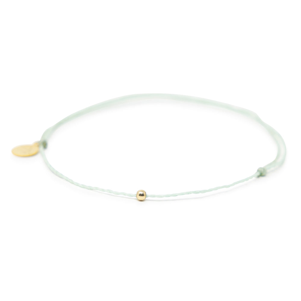 Cucumber mint color thread anklet with a gold filled bead on white front view