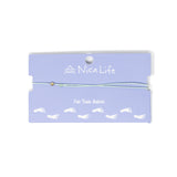 Light mint string anklet with a single gold filled bead on purple Nica Life branded card