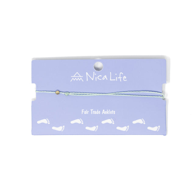 Light mint string anklet with a single gold filled bead on purple Nica Life branded card