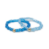 Two cute blue shades of seed bead rings with gold filled bead shown on white