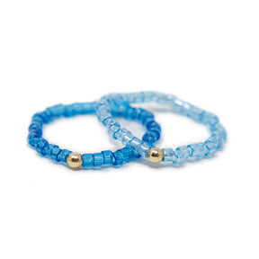 Two cute blue shades of seed bead rings with gold filled bead shown on white