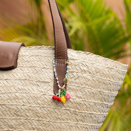 Woven straw bag with a hand beaded charm base & lemon, cherry, & strawberry charms in a tropical setting