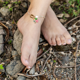 Bright colored anklet charm bar with strawberry and stone charms shown on a model at the lake