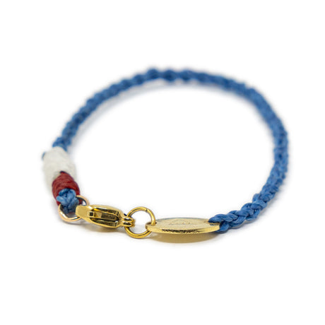 Bag charm with blue cord and gold clasp on a white background