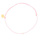 Pink thread anklet on white with single gold filled bead on white top view