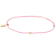 Pink thread anklet on white with single gold filled bead on white