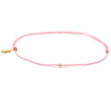Pink thread anklet on white with single gold filled bead on white