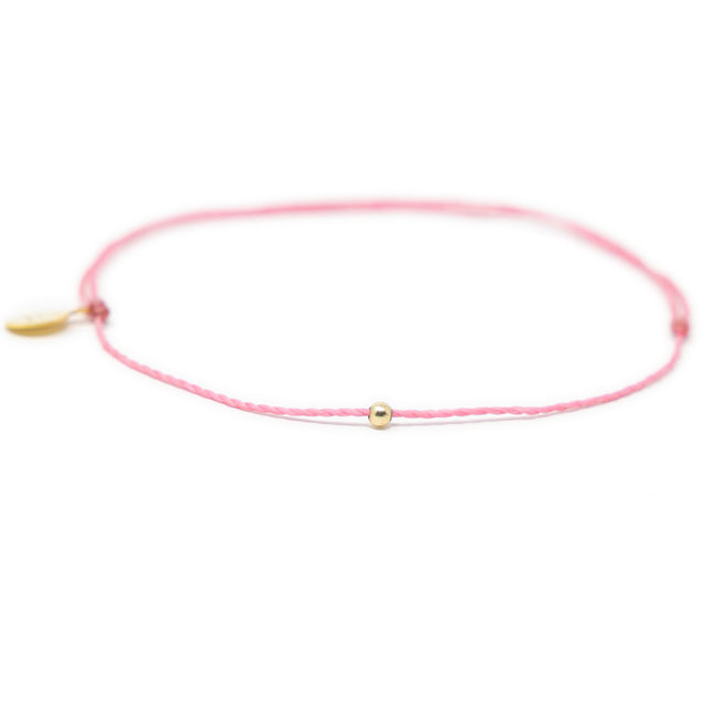 Pink thread anklet on white with single gold filled bead on white