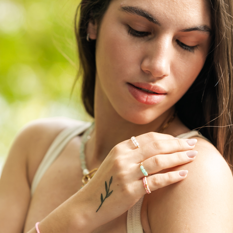 Woman with a small tattoo on her wrist outdoors showing stacking rings in pink and teal colors