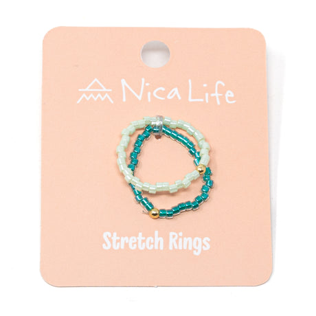 Set of two green seed beaded stretch rings each with a gold filled bead on a 'pink Nica Life' branded card

