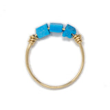 Three turquoise stones on a gold ring shown on whhite top view