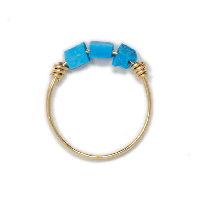 Three turquoise stones on a gold ring shown on whhite top view