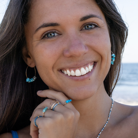 turquoise chip bead earrings with blue stacking rings (turquiose, amazonite, and seed bead) shown on model at the beach