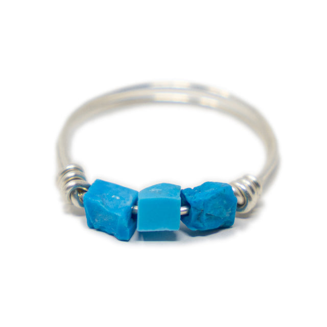 Three raw turquoise stones on silver ring shown on white