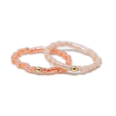 Two pink beaded rings with gold beads on a white background