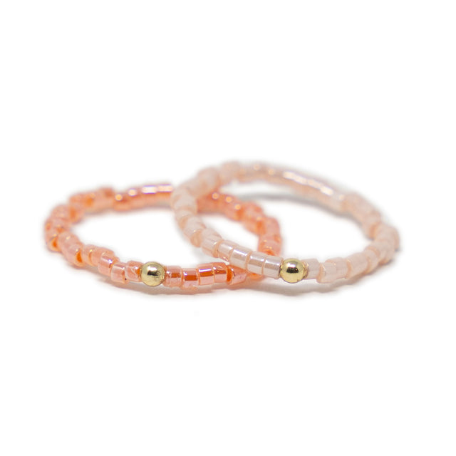 Two pink beaded rings with gold beads on a white background