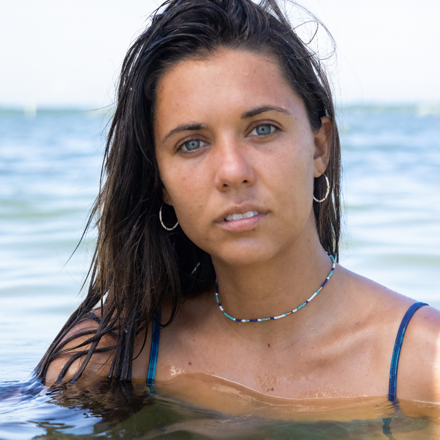Woman in the water wearing a blue and teal seed bead choker and white & gold hoop earrings