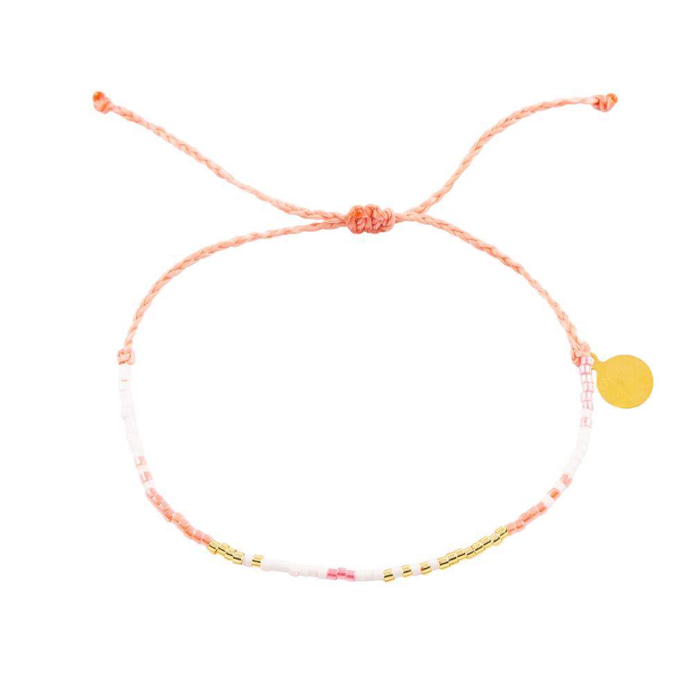 Coral pink and gold seed bead bracelets on white shown fro the top