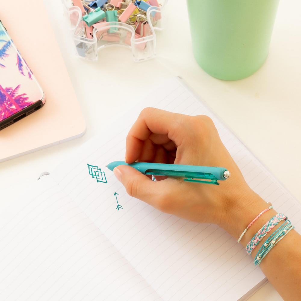 Three coordinating pink & teal bracelets on a woman writing in a notepad